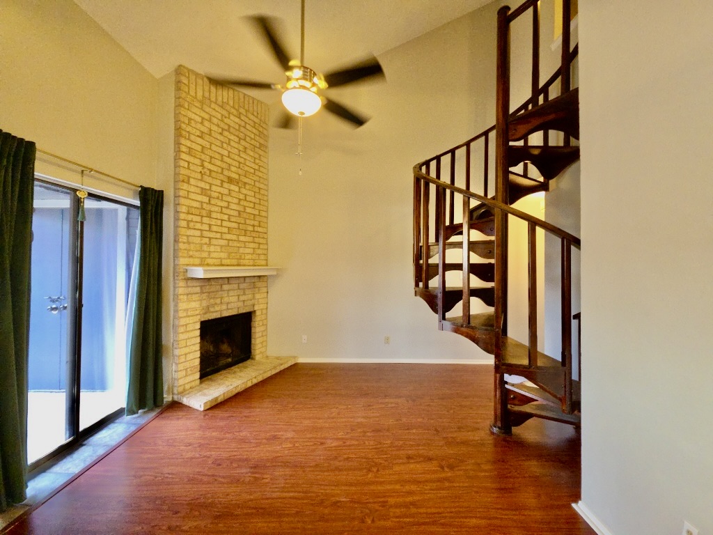 2500 Burleson Road, Unit 521 Austin, TX 78741 - Photo 4 of 20 Spacious living area featuring wood-finish flooring, a brick fireplace with a stone mantel, and vaulted ceilings
