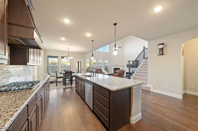 a kitchen with stainless steel appliances granite countertop a sink a stove and a wooden floors