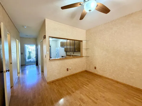 a view of a room with wooden floor and a ceiling fan