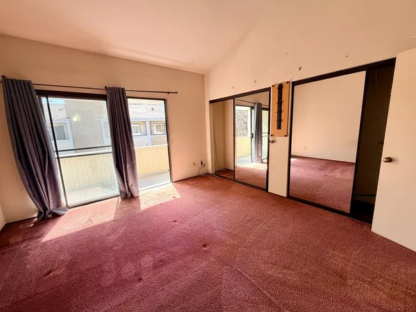 an empty room with closet and windows