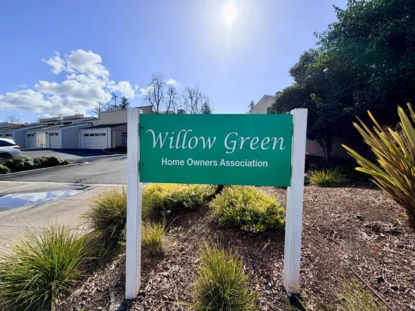 a view of a patio with table and chairs and a barbeque with potted plants and large trees