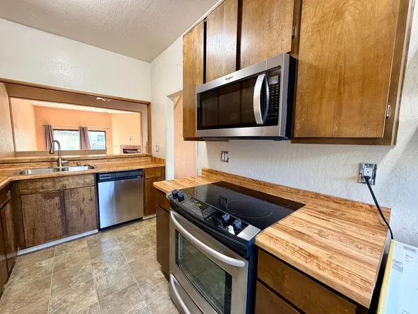 a kitchen with stainless steel appliances granite countertop a stove a microwave and wooden cabinets