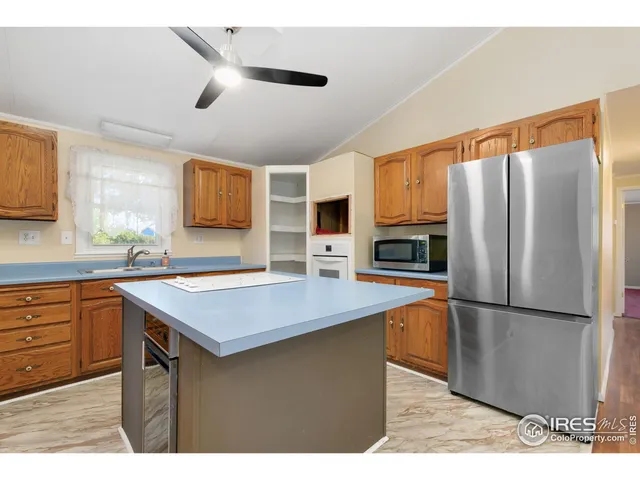 a kitchen with stainless steel appliances granite countertop a refrigerator a sink dishwasher a stove with white cabinets and wooden floor