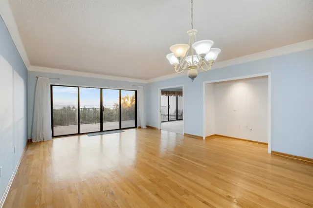 a view of an empty room with wooden floor and kitchen