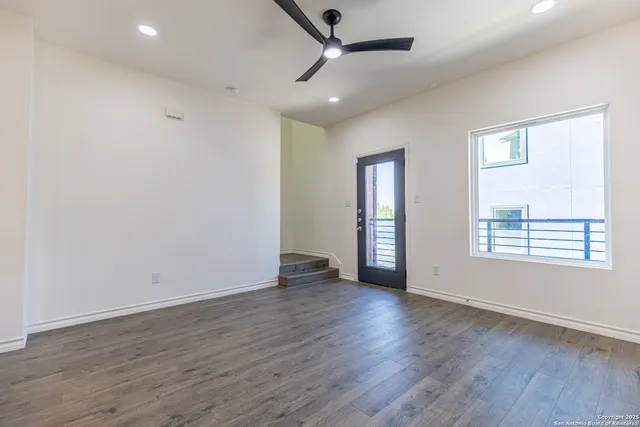 a room with stainless steel appliances kitchen island granite countertop wooden floors and view living room