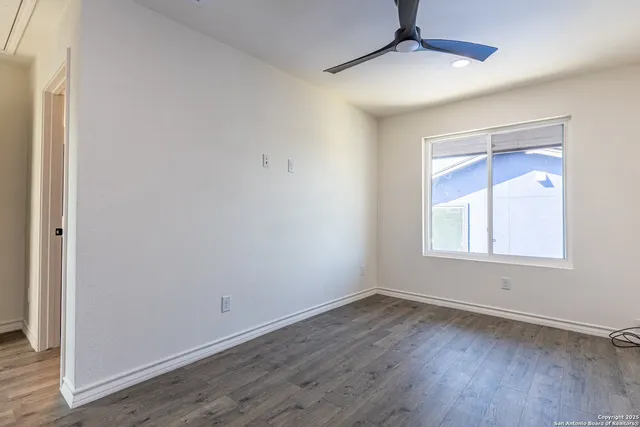 an empty room with wooden floor and ceiling fan