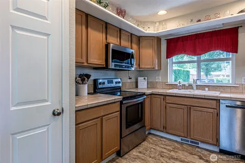 a kitchen with stainless steel appliances granite countertop a stove sink microwave and window