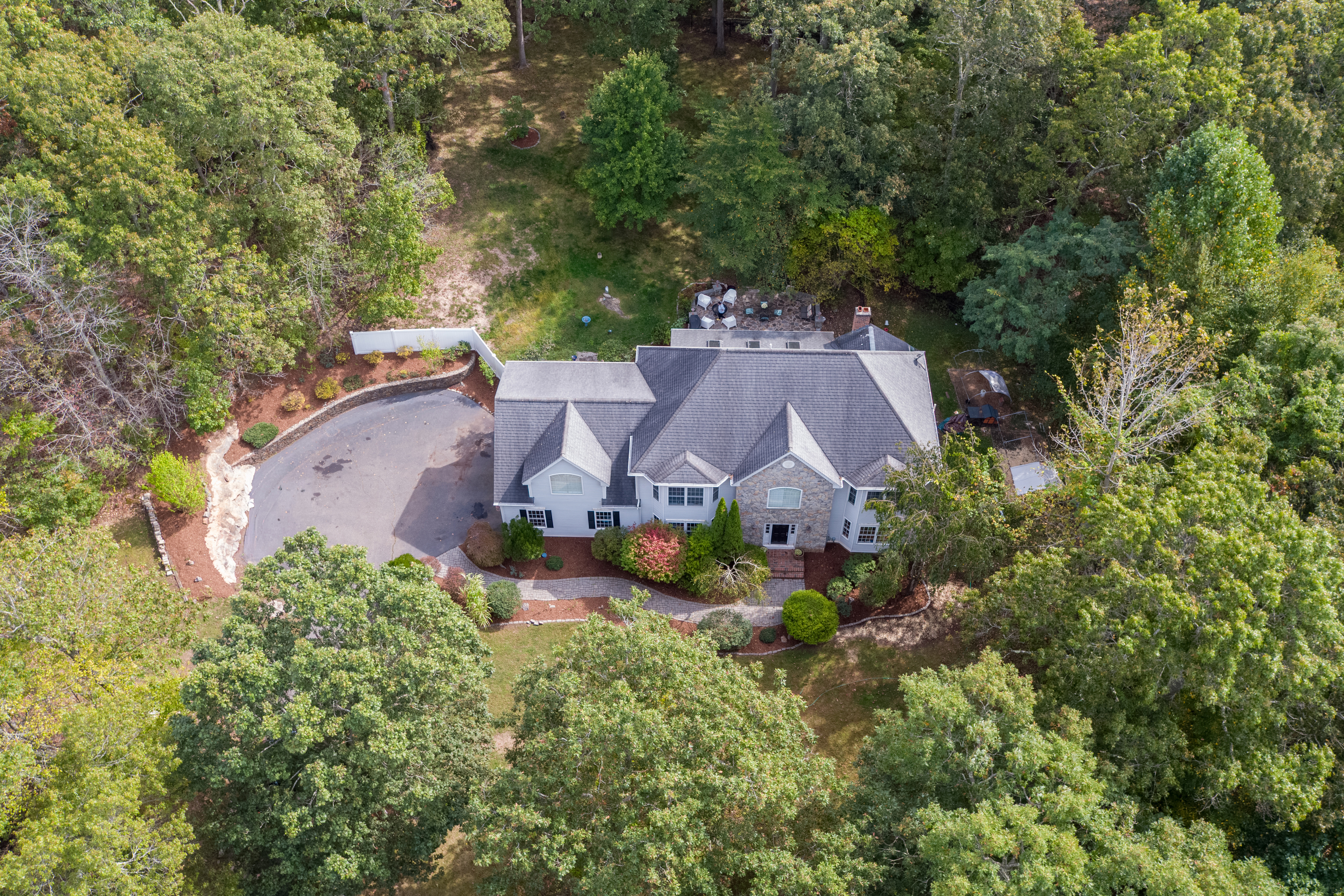 an aerial view of a house with an outdoor space pool stove and trees all around