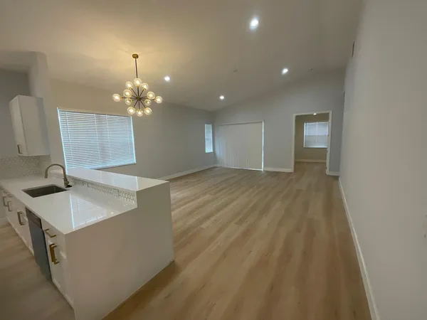 a large white kitchen with kitchen island a sink dishwasher a stove and a refrigerator with wooden floor