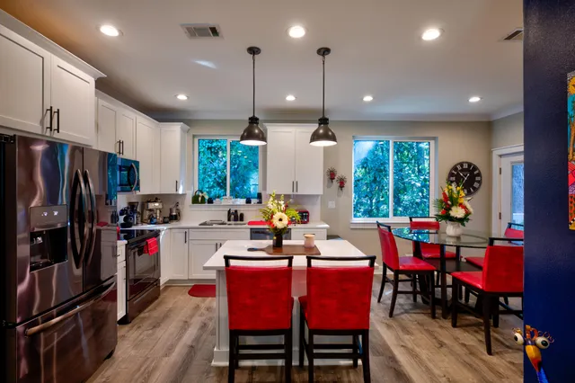 a kitchen with stainless steel appliances granite countertop a stove a refrigerator a kitchen island a dining table and chairs with wooden floor