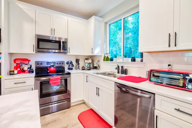 a kitchen with stainless steel appliances granite countertop a sink dishwasher and white cabinets with wooden floor