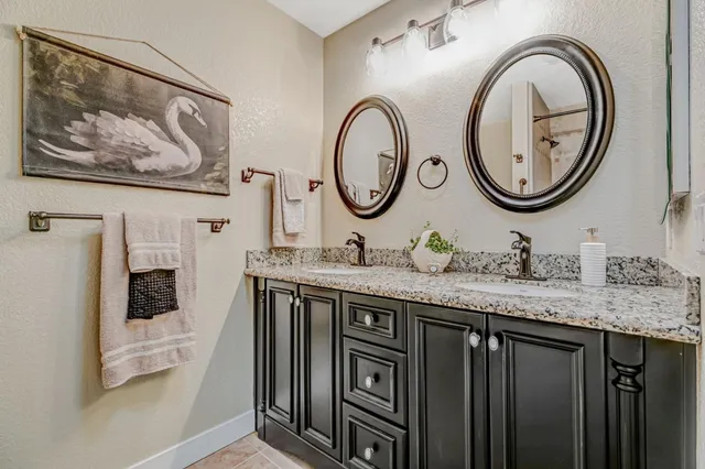a bathroom with a granite countertop double vanity sink and a two mirror
