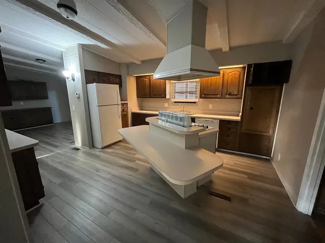 a kitchen with stainless steel appliances a stove a sink dishwasher a refrigerator and wooden floor