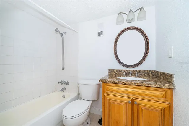 a bathroom with a granite countertop toilet sink and mirror