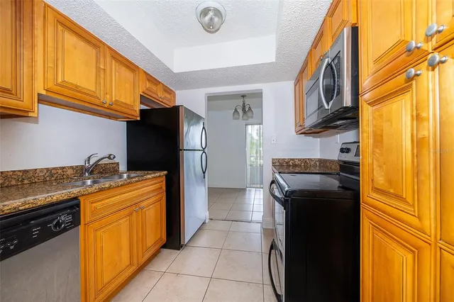 a kitchen with stainless steel appliances granite countertop a refrigerator a stove and a sink