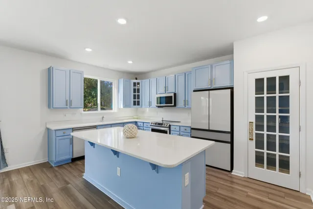 a kitchen with stainless steel appliances a sink a stove a refrigerator cabinets and a kitchen island