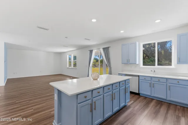 a kitchen with a sink cabinets wooden floor and a window