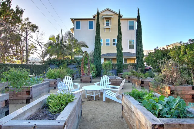 a view of a patio with table and chairs potted plants and floor to ceiling window