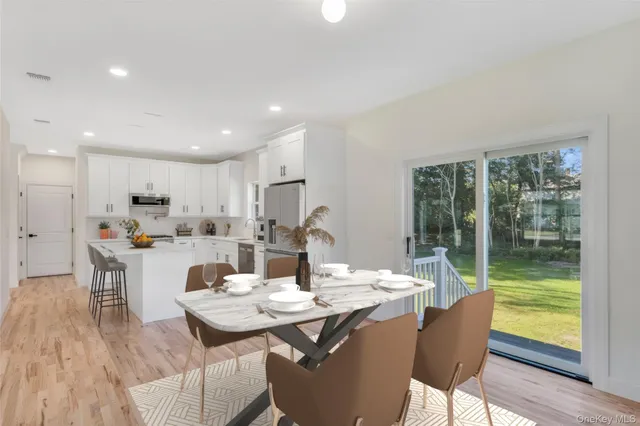 a kitchen with stainless steel appliances a sink dishwasher a stove top oven a refrigerator with white cabinets and wooden floor