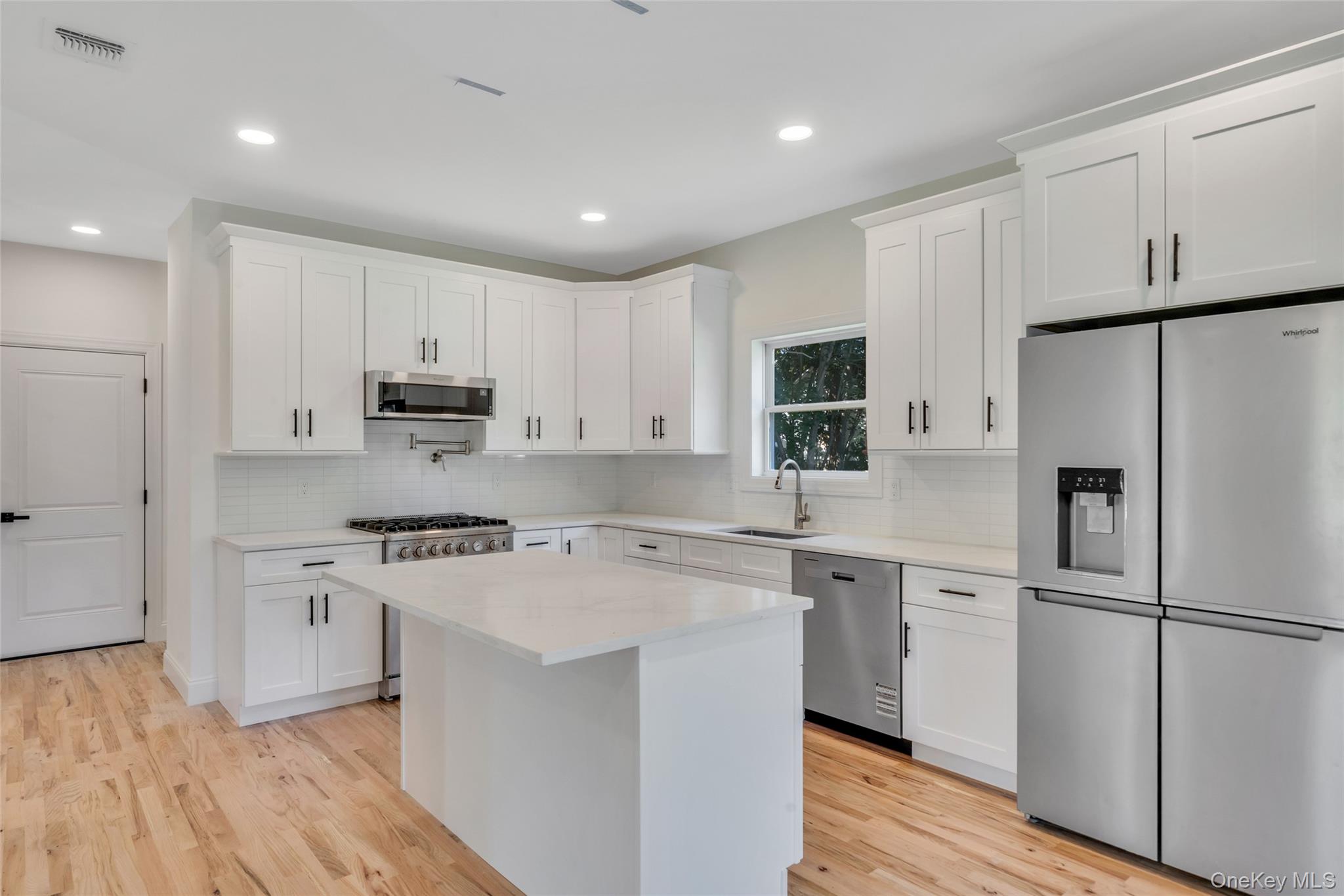 817 Pond View Road Riverhead, NY 11901 - Photo 23 of 36 a kitchen with cabinets stainless steel appliances a sink and wooden floor