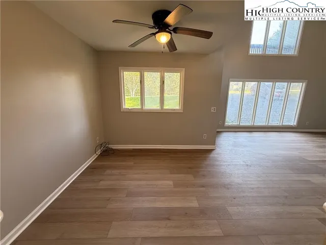 a view of an empty room with window and wooden floor