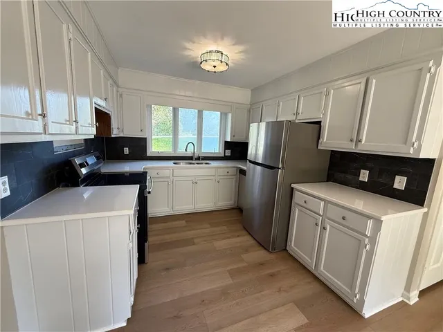 a kitchen with a sink a stove a refrigerator a center island and a window