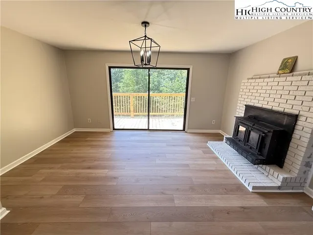 a view of an empty room with wooden floor fireplace and a window