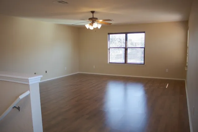 an empty room with wooden floor and windows