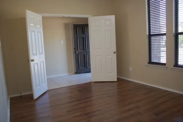 an empty room with wooden floor and windows