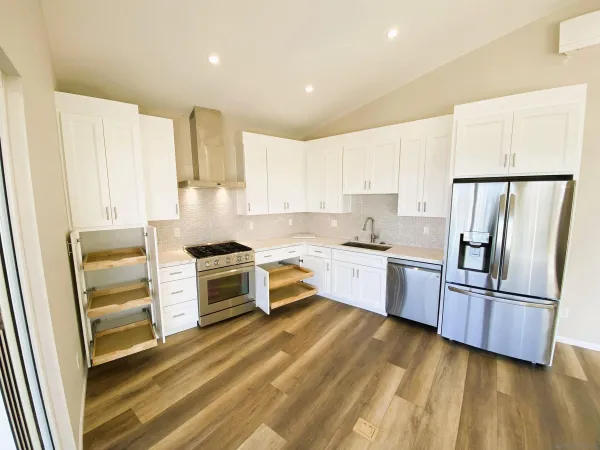 a kitchen with granite countertop a refrigerator stove and wooden cabinets