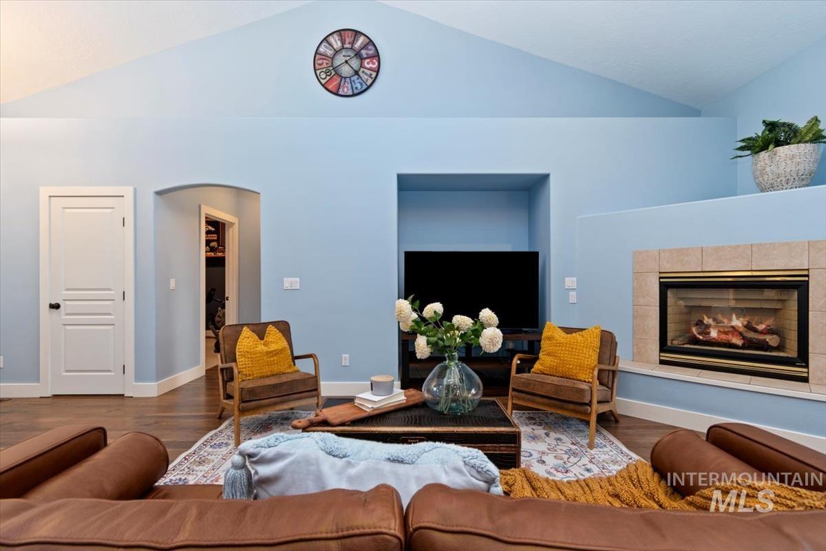 10462 West Lanktree Gulch Road Star, ID 83669 - Photo 7 of 48 Spacious living area featuring vaulted ceilings, wood-finish flooring, a built-in fireplace with tile surround and hearth, an arched doorway, and built-in shelving