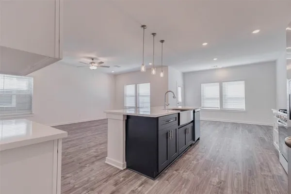 a kitchen with stainless steel appliances granite countertop a sink a stove top oven a refrigerator with white cabinets and wooden floor