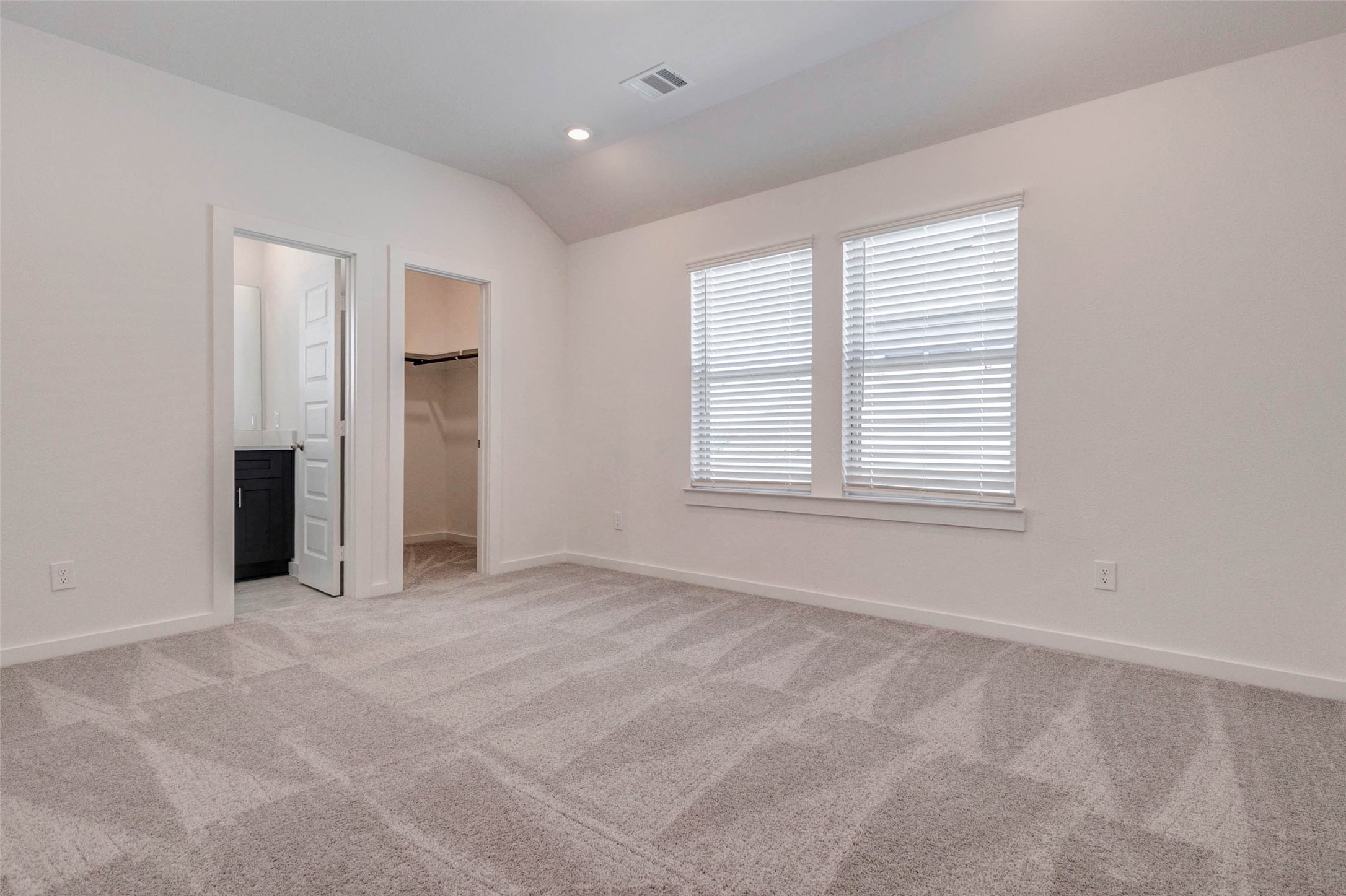 1038 Elsinore Drive Rosharon, TX 77583 - Photo 18 of 27 The spacious primary bedroom offers a peaceful retreat with soft plush carpeting, vaulted ceilings, and abundant natural light pouring in through large dual windows. The generous layout easily accommodates a full bedroom suite while maintaining an open and airy feel. Direct access to the private en-suite bathroom and walk-in closet enhances everyday comfort, making this relaxing space the perfect place to unwind after a long day.