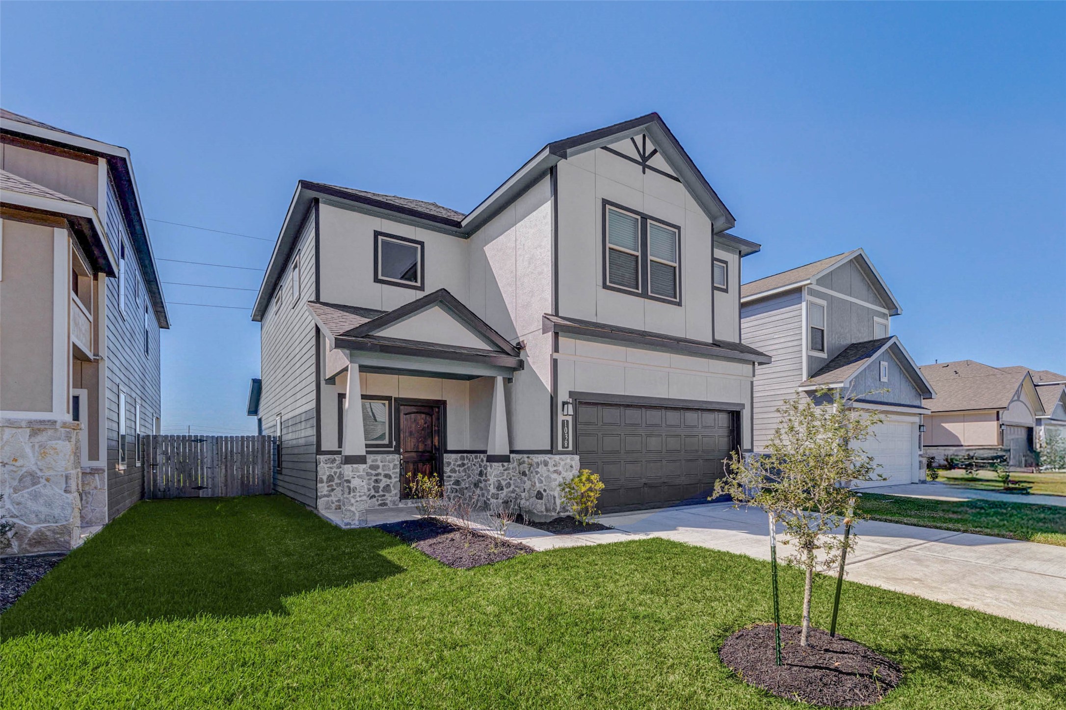 1038 Elsinore Drive Rosharon, TX 77583 - Photo 2 of 27 An angled exterior view showcases the home’s thoughtful design, combining modern finishes with classic suburban charm. The covered front porch provides a welcoming entry and a perfect spot to greet guests, while the fresh landscaping and newly planted trees add to the home’s curb appeal. Clean architectural lines, stone accents, and contrasting trim details create a stylish yet inviting look that stands out beautifully in the neighborhood.