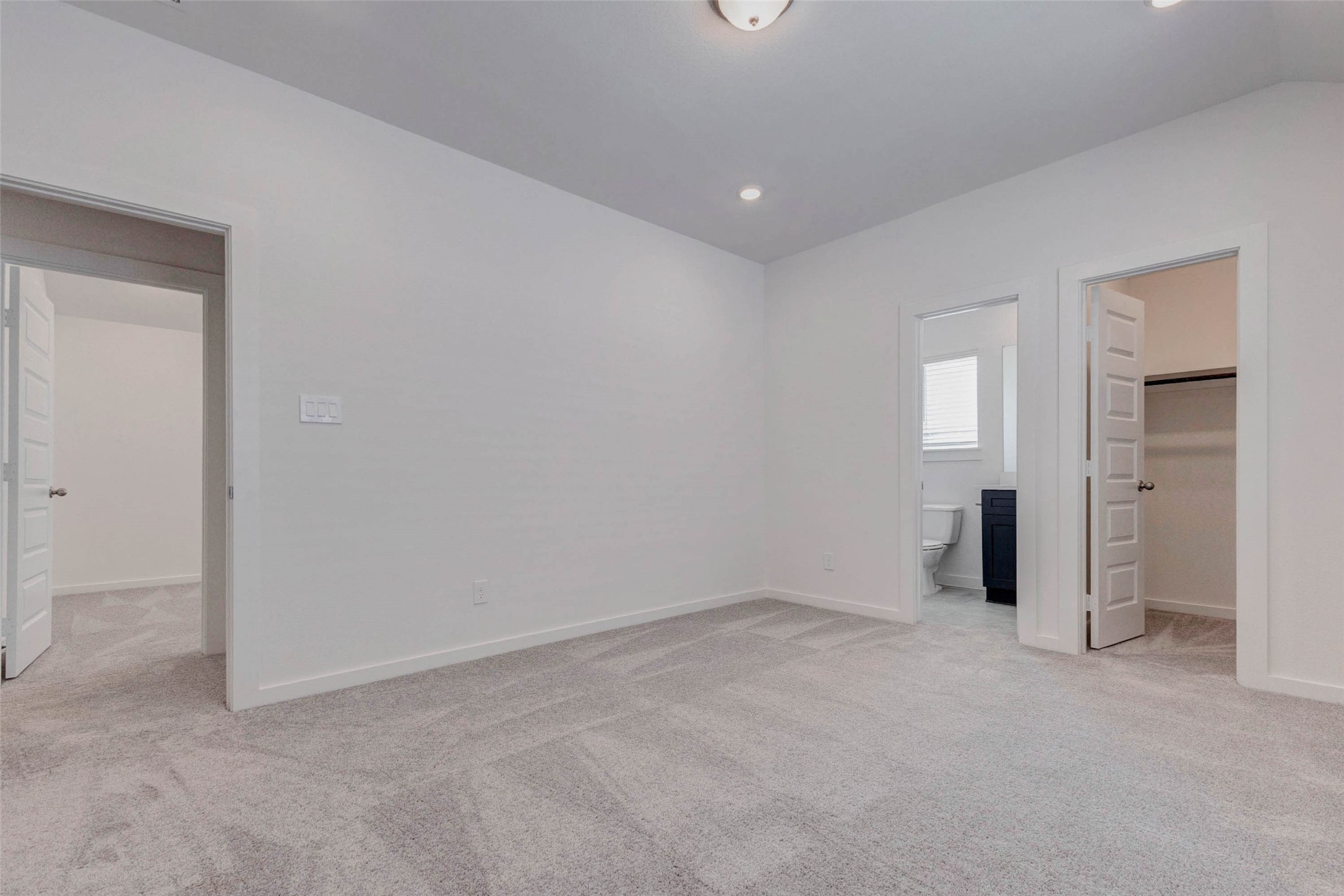 1038 Elsinore Drive Rosharon, TX 77583 - Photo 19 of 27 This alternate view of the primary suite highlights the expansive floor space and thoughtful layout that allows for flexible furniture arrangements. The neutral color palette and fresh carpeting create a calm and inviting atmosphere, while recessed lighting and high ceilings enhance the sense of openness. With easy access to the private bathroom and large walk-in closet, this room blends comfort, function, and modern design.