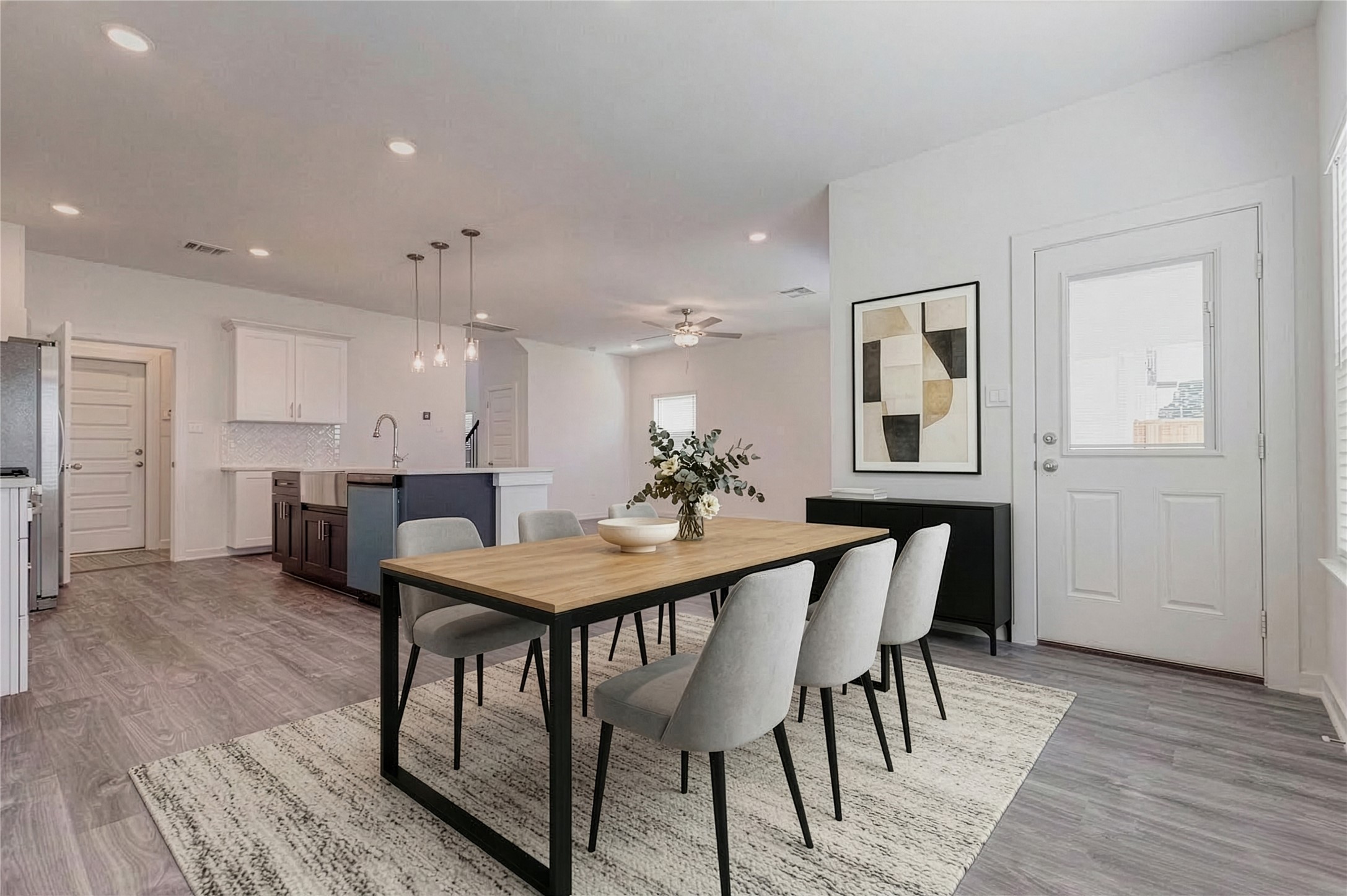 1038 Elsinore Drive Rosharon, TX 77583 - Photo 25 of 27 This wide view captures the expansive open living area designed for comfort and versatility. The spacious floor plan offers endless possibilities for furniture placement, entertainment setups, or a combined living and dining arrangement. Modern flooring, recessed lighting, and large windows bring warmth and brightness to the room, while the kitchen island remains the stylish centerpiece connecting the entire main floor living space. This photo has been virtually staged for visual reference.