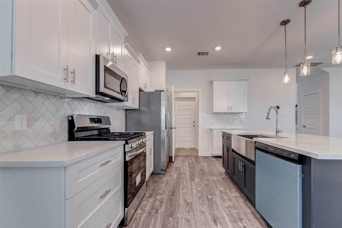 1038 Elsinore Drive Rosharon, TX 77583 - Photo 7 of 27 This beautifully designed kitchen offers both style and practicality with its spacious layout and modern finishes. The stainless steel gas range, built-in microwave, and refrigerator are complemented by elegant cabinetry and a bright backsplash that adds visual texture. The large island features a farmhouse-style sink and additional storage, making this kitchen perfect for cooking, hosting gatherings, and enjoying daily life with ease.