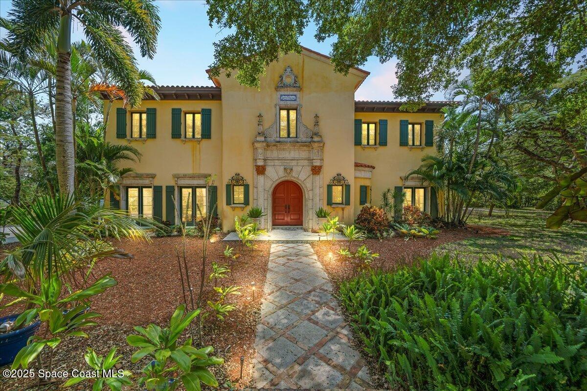 9340 South Tropical Trail Merritt Island, FL 32952 - Photo 82 of 100 a view of a brick house with many windows plants and large trees