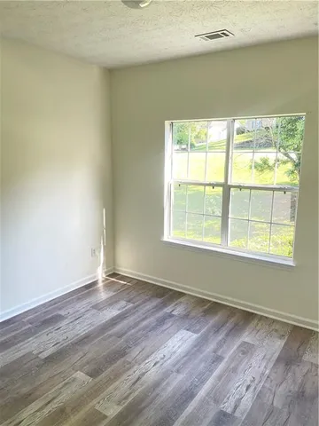 a view of an empty room with a window and wooden floor