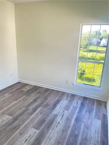 an empty room with wooden floor fireplace and windows