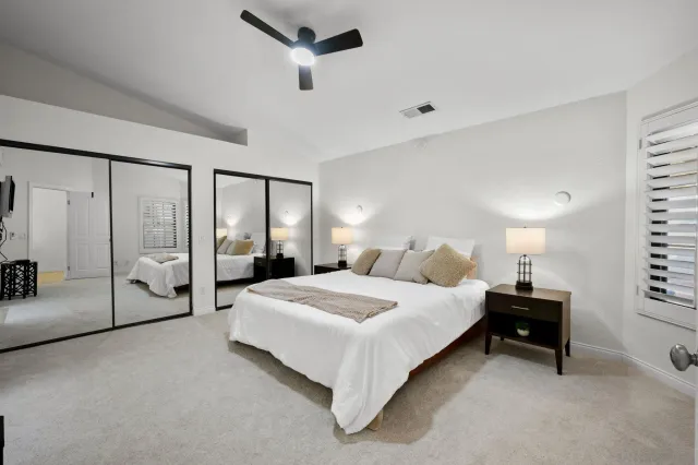 a bedroom with a large bed and a chandelier fan