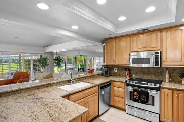 a kitchen with stainless steel appliances granite countertop a stove a sink and a microwave