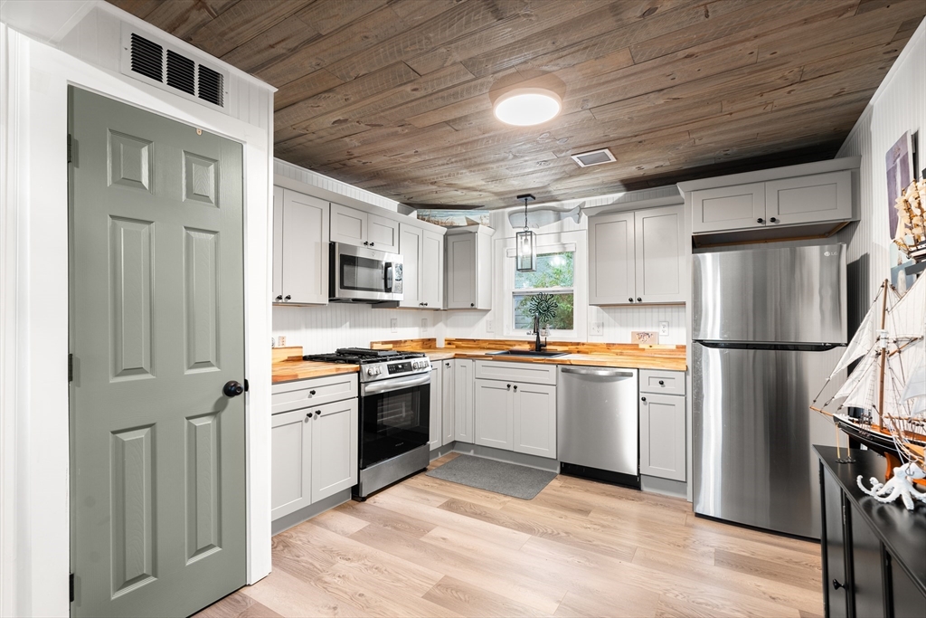 25 Lakeview Drive Wareham, MA 02538 - Photo 11 of 31 a kitchen with stainless steel appliances granite countertop a refrigerator a stove top oven a sink dishwasher and white cabinets with wooden floor