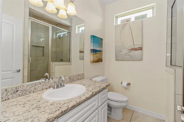 a bathroom with a granite countertop sink mirror vanity and toilet
