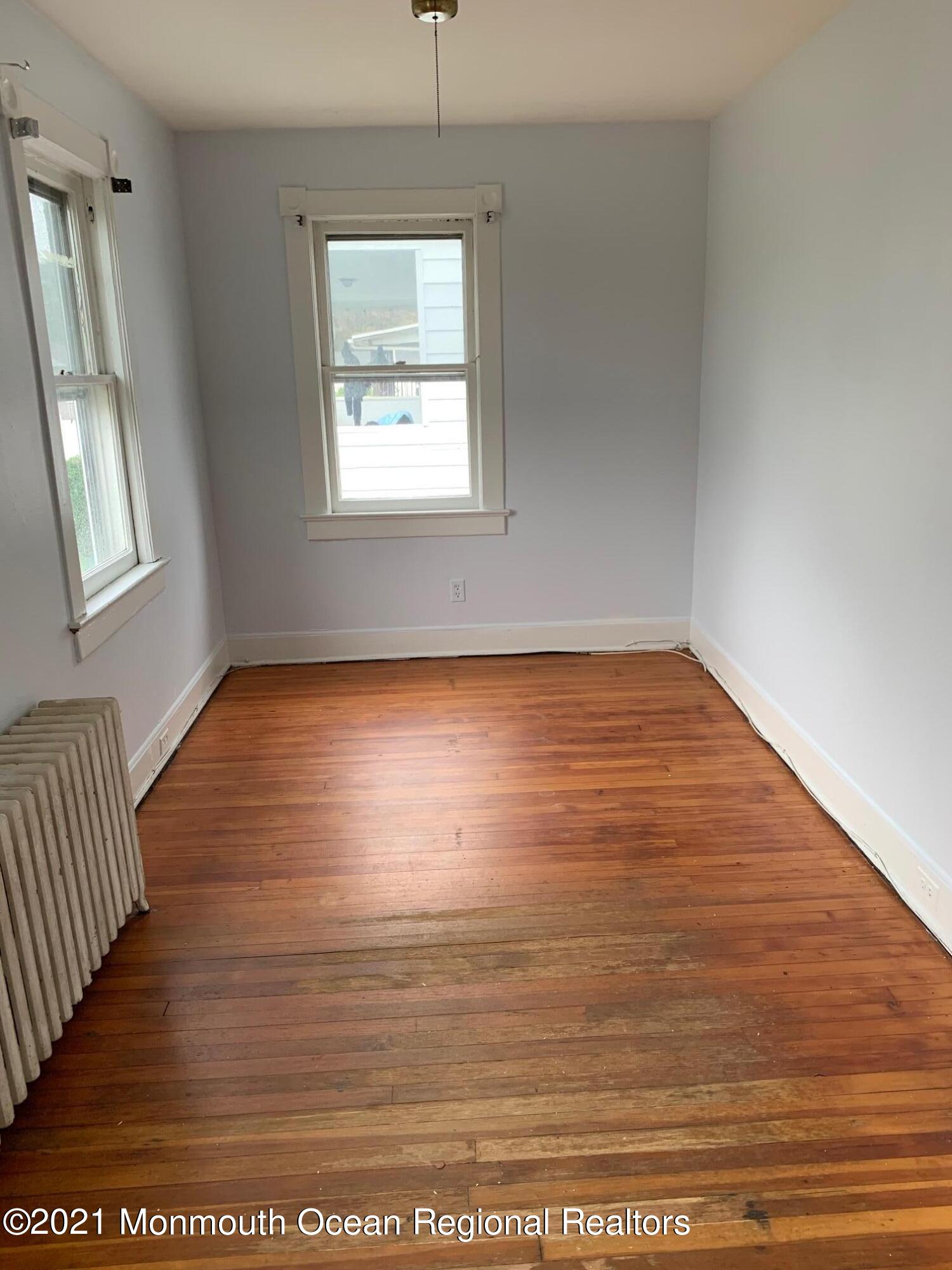 1428 6th Avenue Neptune, NJ 07753 - Photo 6 of 6 an empty room with wooden floor and windows
