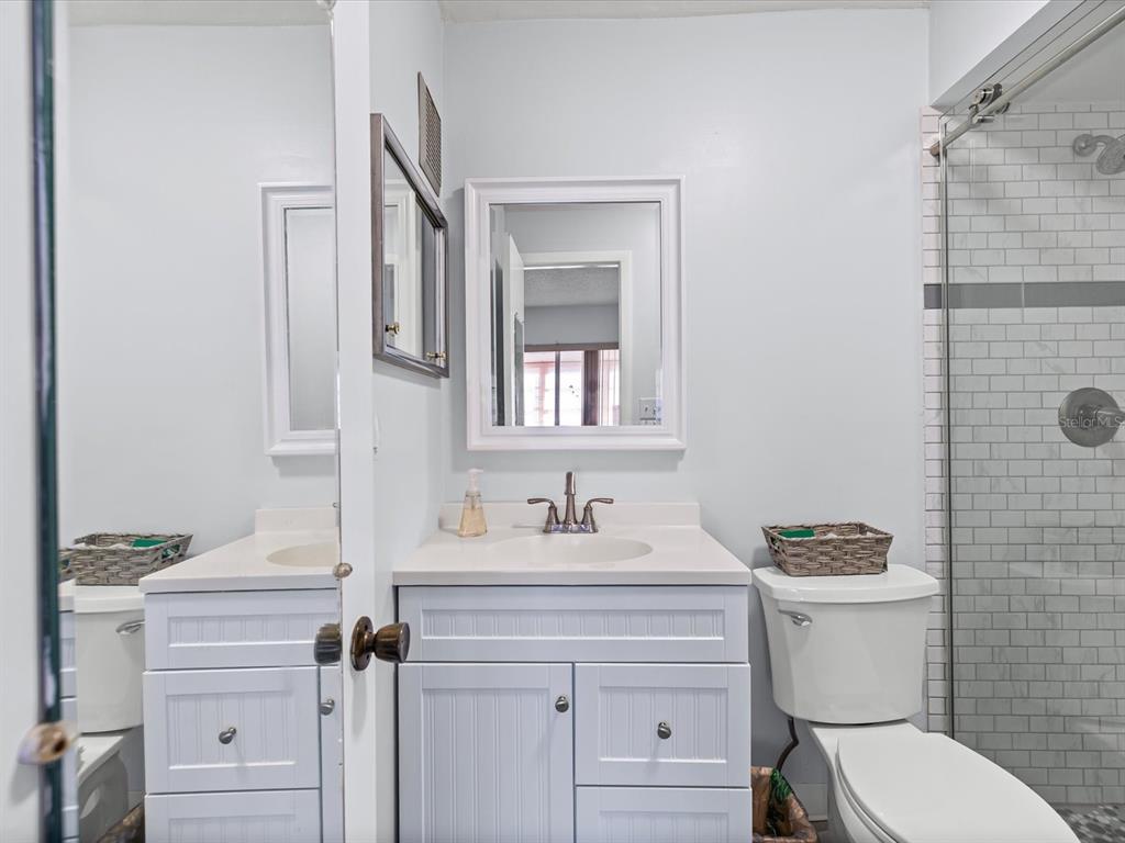 11735 Boynton Lane, Unit 11735 New Port Richey, FL 34654 - Photo 17 of 25 a bathroom with a granite countertop sink toilet a mirror and shower