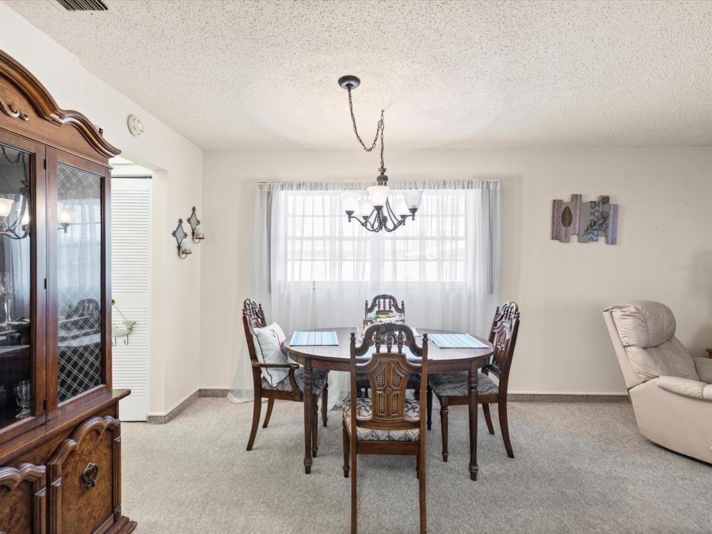 11735 Boynton Lane, Unit 11735 New Port Richey, FL 34654 - Photo 9 of 25 a view of a dining room with furniture and chandelier