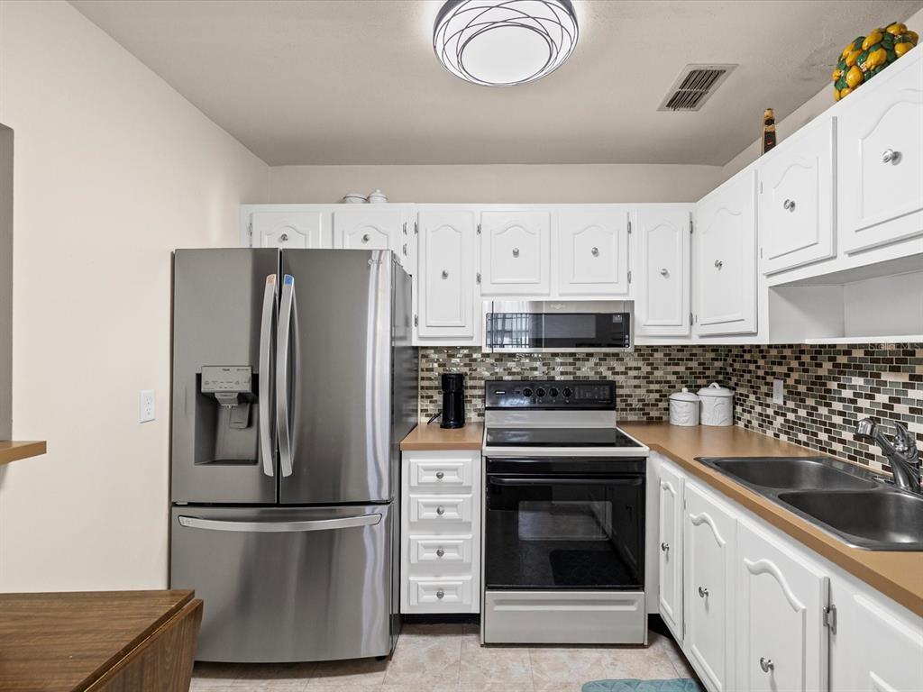 11735 Boynton Lane, Unit 11735 New Port Richey, FL 34654 - Photo 10 of 25 a kitchen with cabinets stainless steel appliances and wooden floor