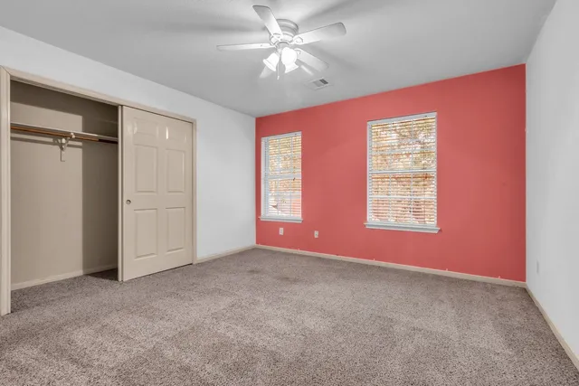 an empty room with windows and fan