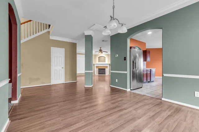 a view of a hallway with wooden floor and a kitchen